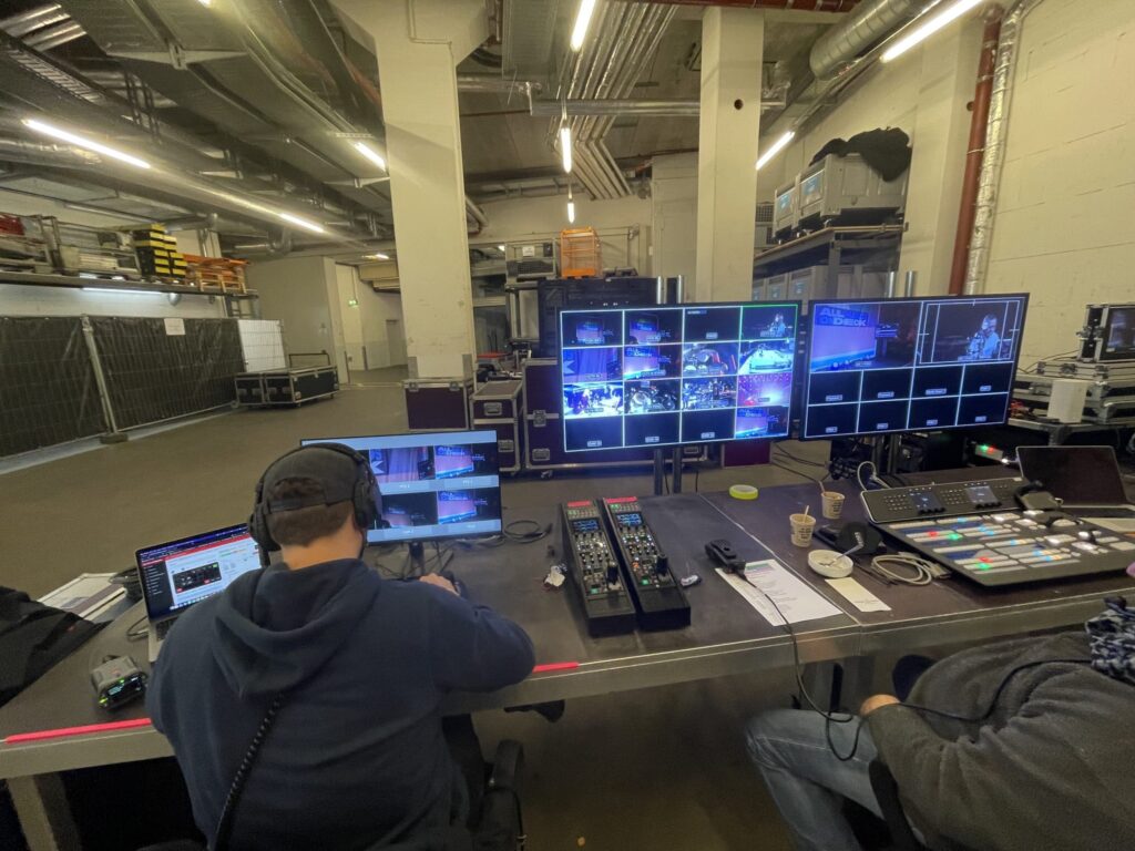 Bürohalle mit Bildschirmen, welche mehrere Videoüberwachungsbilder anzeigen.